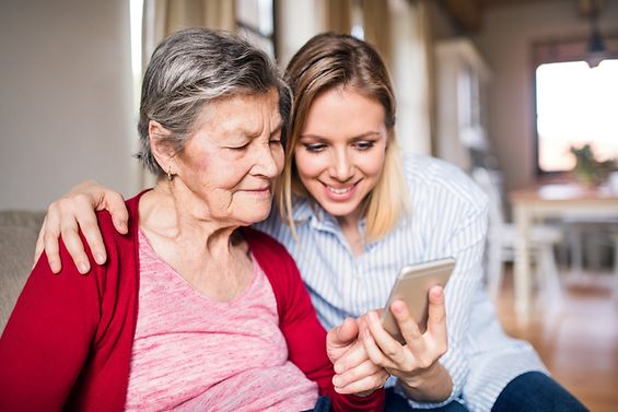 Seniorin und junge Frau schauen gemeinsam auf ein Smartphone
